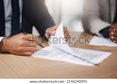 Signing off another big business deal. Closeup shot of two unrecognizable businesspeople going through paperwork in an office.