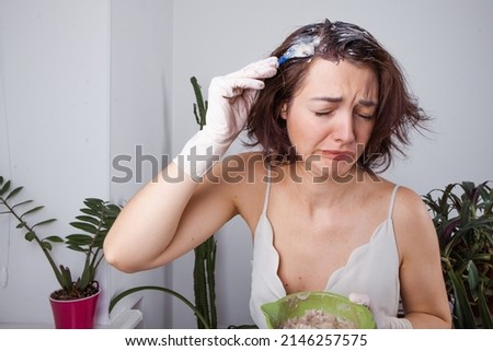 Young woman applying dye on hairs in bathroom. High quality photo