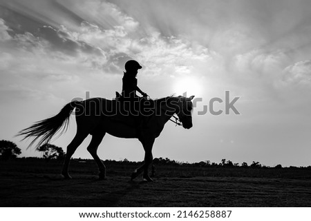 Silhouette of child riding horse in the farm