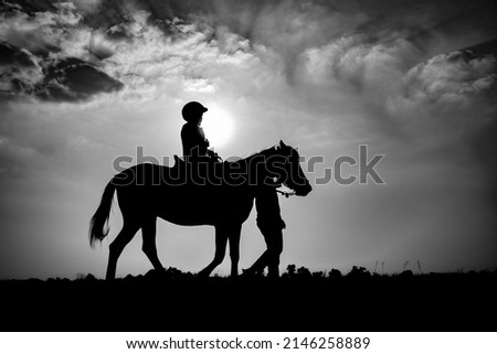 Silhouette of child riding horse in the farm