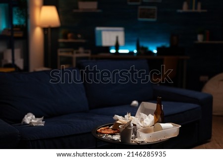 Empty unorganized space with dirty trash and stinky rubbish, messy unfinished food in leftovers cand and beer bottles on untidy table. Nobody in living room with unhealthy garbage. Royalty-Free Stock Photo #2146285935