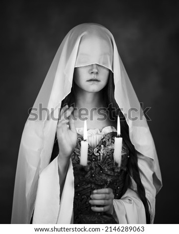 A girl with a thin translucent scarf covered her face and a candlestick in her hands in black and white format