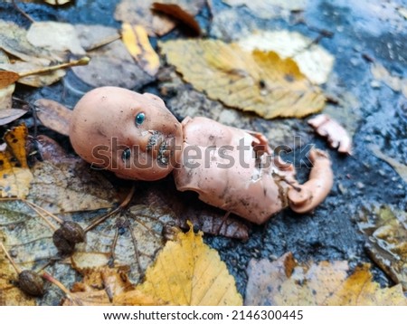 Little broken doll forgotten on the street. Symbol of a broken childhood Royalty-Free Stock Photo #2146300445