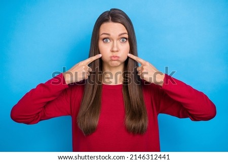Photo of millennial impressed long hairdo lady index cheeks wear red sweater isolated on blue color background