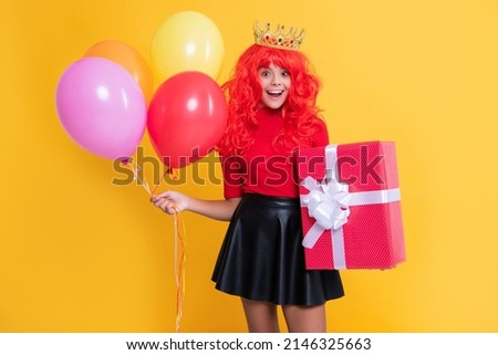 happy surprised child in crown with present box and party balloon on yellow background