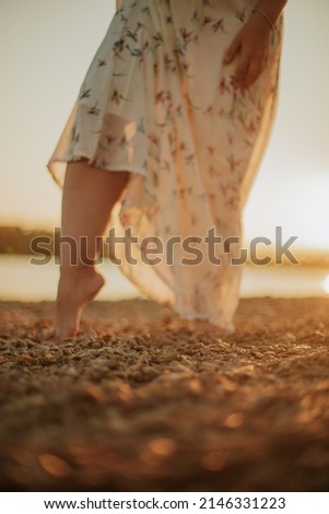 close women's legs walking on the beach at sunset