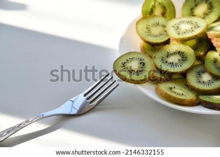 Kiwi fruit slices on a white plate with a fork