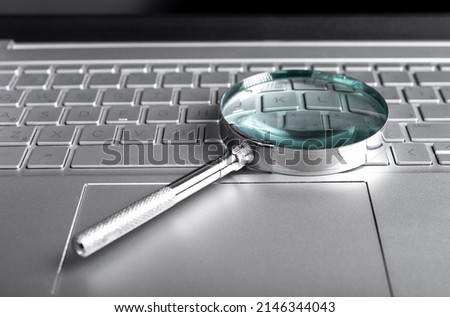 Magnifying glass on laptop keyboard. Internet surfing concept. Online databases study. Audit conducting using computer. High quality photo