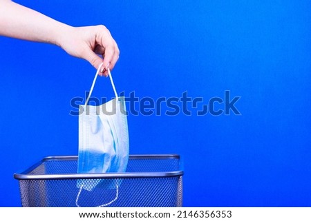 medical mask are thrown the trash on a blue background