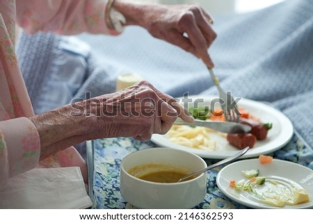 Elderly lady eating healthy lunch in bed. Old age home. Frail care. vegetables. Sausage. Soup. Royalty-Free Stock Photo #2146362593
