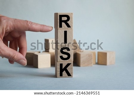 RISK inscription on wooden cubes texture. Close-up of a man's hand points to a cube. The inscription on the financial, business or economic theme.