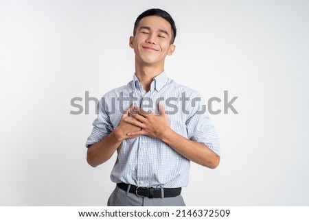 young man holding chest feeling relieve and comforting himself Royalty-Free Stock Photo #2146372509