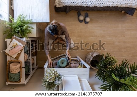 Top view woman knitted clothes and accessories designer tidying up ribbon yarn needles cupboard storage organization. Creative female art craft hobby or work placing details on shelves filling cabinet Royalty-Free Stock Photo #2146375707