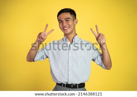 asian man with cute hand gesture making v shape on finger Royalty-Free Stock Photo #2146388121
