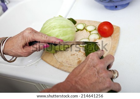 Cropped image of senior woman chopping vegetables on cutting board in kitchen