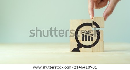 Cost reduction concept. Lean manufacturing management. Decreasing company expense cost to maximize profits. Putting wooden cube with focusing cost reduction symbol. .Business survival and improvement. Royalty-Free Stock Photo #2146418981