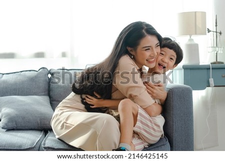 Happy Asian tender son hugging mother on mother's day during holiday celebration at home. Royalty-Free Stock Photo #2146425145