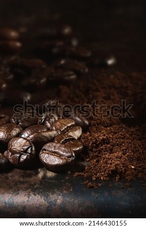 Fragrant freshly roasted coffee beans and ground coffee are scattered on a metal tray. Close-up, selective focus, vertical frame.