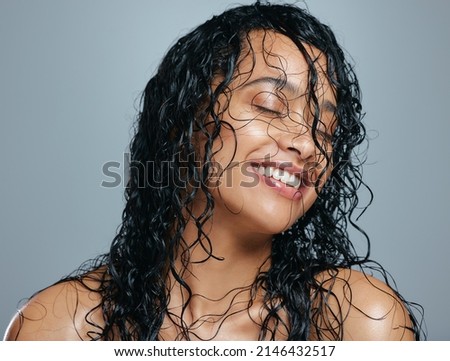 Keeping her mane a head about the rest. Studio shot of an attractive young woman posing with wet hair against a grey background. Royalty-Free Stock Photo #2146432517