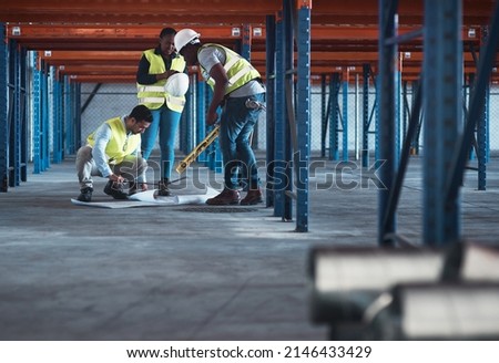 We speak engineer fluently. Shot of a group of contractors using a blueprint to plan in the warehouse. Royalty-Free Stock Photo #2146433429
