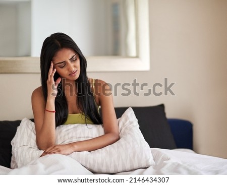 What could be causing these morning migraines. Shot of a young woman waking up in the morning feeling unwell. Royalty-Free Stock Photo #2146434307