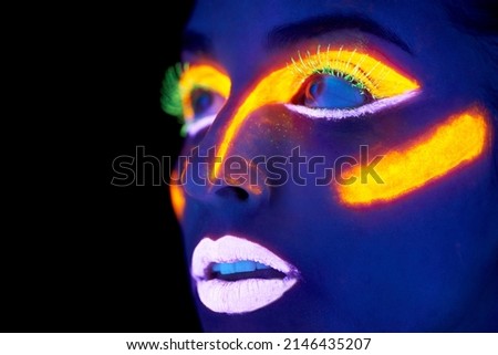 Neon celebration. A young woman with with neon paint on her face posing. Royalty-Free Stock Photo #2146435207
