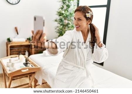 Young latin woman wearing bathrobe male selfie by the smartphone 