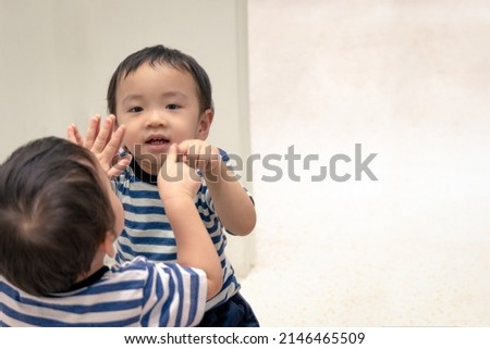 Portrait of happy asian boy smile while pointing his finger into his reflection in the mirror. Royalty-Free Stock Photo #2146465509