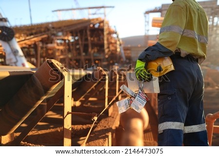 Safe work practise miner wearing work uniform safety glove holding hard hat danger personal safety locks preparing to locking on isolation convertor belt prior working on site