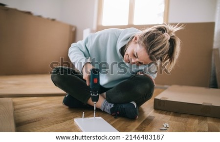 Woman assembling furniture at home with cordless screwdriver Royalty-Free Stock Photo #2146483187