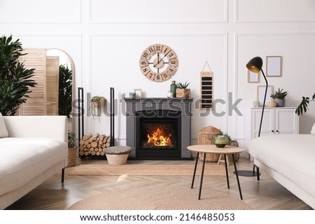 Stylish living room interior with electric fireplace, comfortable sofas and beautiful decor elements