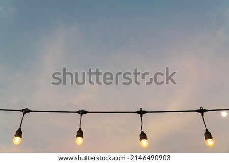 Photo of Hanging light bulbs on sky background. retro luxury light lamp decor glowing. Sunset scene of light bulbs. vintage light bulbs.