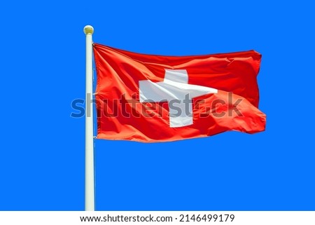 Switzerland flag waving against clean blue sky, close up. Swiss flag in the blue sky. Flag Switzerland on blue sky background