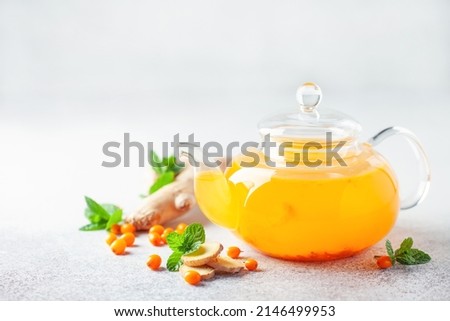 Hot autumn tea with sea buckthorn, ginger and mint in a glass teapot on a gray background Royalty-Free Stock Photo #2146499953