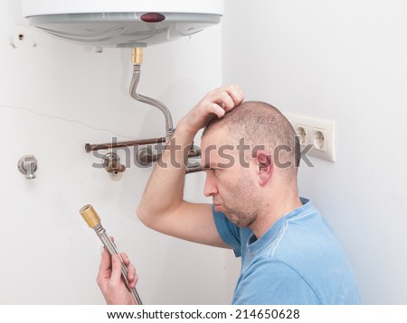 Inexperienced plumber trying to repair an electric water heater Royalty-Free Stock Photo #214650628