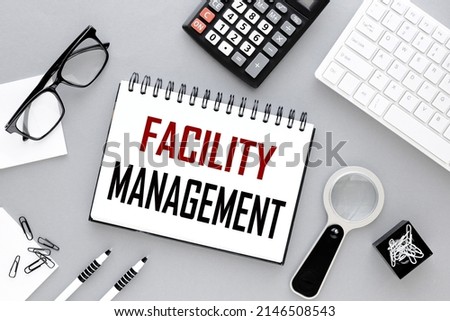 Facility management. text on open notepad on gray background near white keyboard calculator