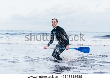 Surfer with a paddle surf rhythm jumping and standing on the blue can picafort beach in Majorca. Majorca Balearic Islands