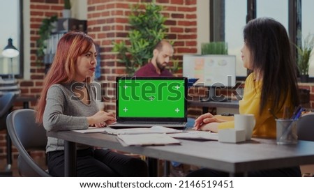 Business people looking at laptop with green screen and working to develop partnership. Coworkers using isolated mockup template with chroma key background and copy space on computer.