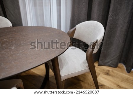 light chair made of soft fabrics and wood at a dark wooden table in the interior of the house