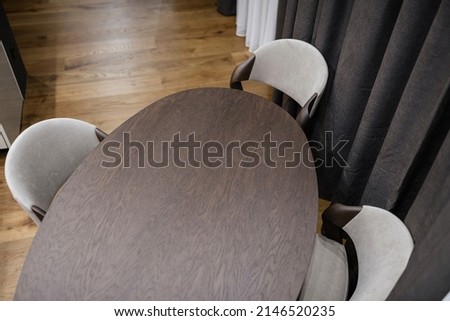 dark wooden oval clean new table and light soft chairs in the interior of the house. top view