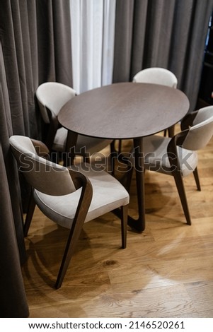 large new clean table made of natural dark wood and light chairs in the interior of the house