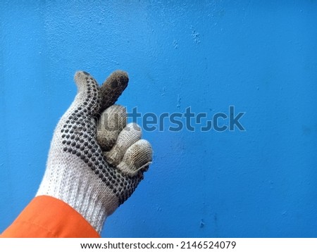 Man hand in work glove  love sign isolated on blue background. Showing Gesture  loving the Work. Good job, fun mood and passion concept. Copy space photo
