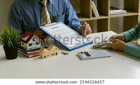 The sales representative offers a home purchase contract and presents the project close to the new homeowner's clients when they sign the purchase or lease agreement on their workspace table.