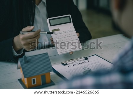The sales representative offers a home purchase contract and presents the project close to the new homeowner's clients when they sign the purchase or lease agreement on their workspace table.