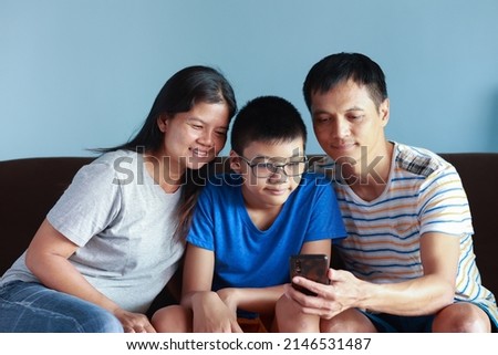 Portrait of Thai family with parents and sons. It is a picture that feels full of love and warmth. sitting on the sofa in the house Father and mother take good care of their children.