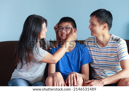 Portrait of Thai family with parents and sons. It is a picture that feels full of love and warmth. sitting on the sofa in the house Father and mother take good care of their children.