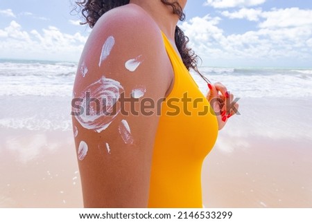 brown skin with sunscreen. Woman applying sun cream on her body. drawing with a sun cream on the arm