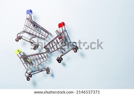 Three metal grocery baskets with colored handles on a light background top view. The concept of business and trade.