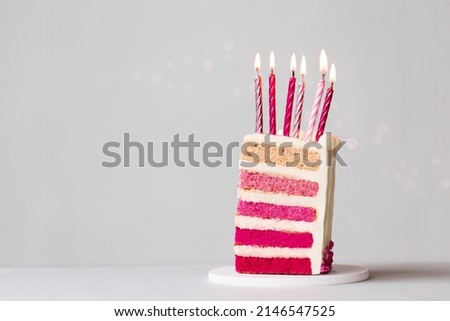 Slice of pink ombre birthday cake with six pink birthday candles to celebrate a birthday