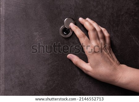 Door peephole and hand. peephole close-up. female hand opens the door peephole cover. Close-up. Side view. Place to copy. Royalty-Free Stock Photo #2146552713